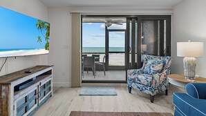 Een woonkamer met uitzicht op het strand, een plafondventilator en een gestreept fauteuil.