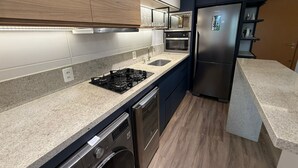 A modern kitchen with a gas stove, oven, microwave, and stainless steel refrigerator. - RCM Vilas - Apartamento Sofisticado (Joinville)