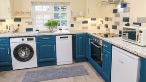 Une cuisine moderne avec des meubles bleus, un lave-vaisselle Bosch, un four Bosch et un four à micro-ondes.