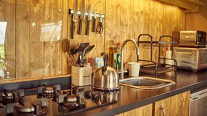 A kitchen with wooden cabinets, a stainless steel sink, a kettle, and various utensils. - Bramley Lodge (Glastonbury)