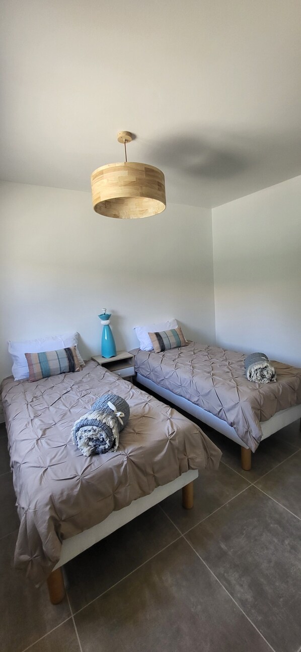A bedroom with two beds, a wooden ceiling light, and a blue vase on a nightstand. - Casa Orizonte, Villa, Viggianello Heights, View on the Valinco gulf (Viggianello)