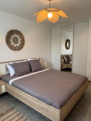 A modern bedroom with a wooden bed, a round mirror, and a unique ceiling light fixture. - Casa Orizonte, Villa, Viggianello Heights, View on the Valinco gulf (Viggianello)