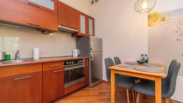 Una cocina compacta con armarios de madera, un refrigerador de acero inoxidable y una zona de comedor con mesa y sillas de madera.