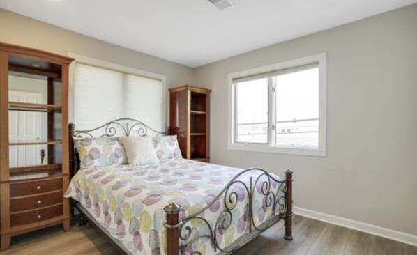 A bedroom with a bed, wooden nightstands, a wardrobe, and a window. - Charming 3-bedroom townhome with WiFi, AC in Seaside Heights (Seaside Heights)