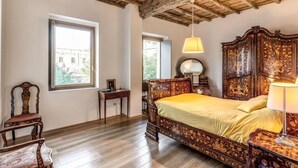 A bedroom with a large bed, wooden furniture, and a view through a window. - Authentic Roman Escape with Private Terrace & City views (Roma)