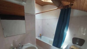 Ein Badezimmer mit Waschbecken, Spiegel, Dusche und einem Sessel.