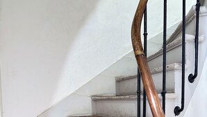 A staircase with wooden steps and a black metal handrail. - VIERGE (Paris)