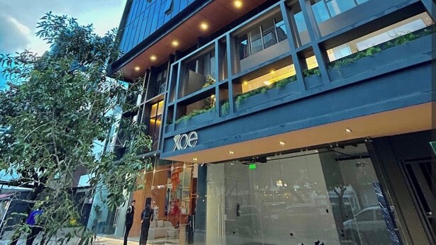 A modern building with a glass facade, a visible entrance, and a sign reading "XOE". - Suite XOE in front of Carolina Park - 11th floor (Quito)
