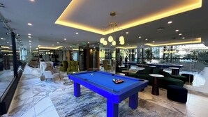 A modern indoor pool area with a blue pool table, comfortable seating, and large windows offering views of the outdoors. - Suite XOE in front of Carolina Park - 11th floor (Quito)
