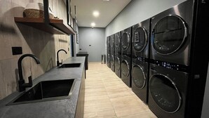 A modern laundry room with multiple washing machines and a sink. - Suite XOE in front of Carolina Park - 11th floor (Quito)