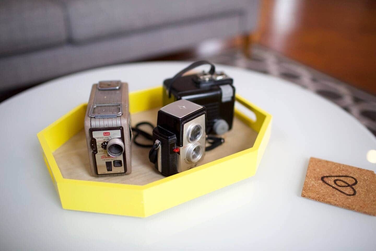 Two vintage cameras in a yellow box on a white table.