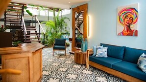A modern interior with a staircase, a blue sofa, and a large painting. - Central Hotel Boutique (Las Galeras)