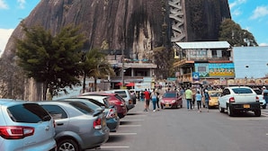 A parking lot with cars and a large mountain in the background. - Suites del Lago (Marinilla)