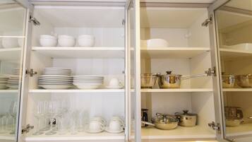 Un mueble de cocina con estantes que contienen cuencos, platos y cristalería blancos.