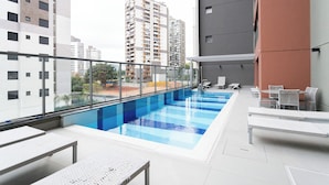 A rooftop swimming pool with lounge chairs and a glass balustrade. - Haus Mitre Alto Butantã (Sao Paulo)