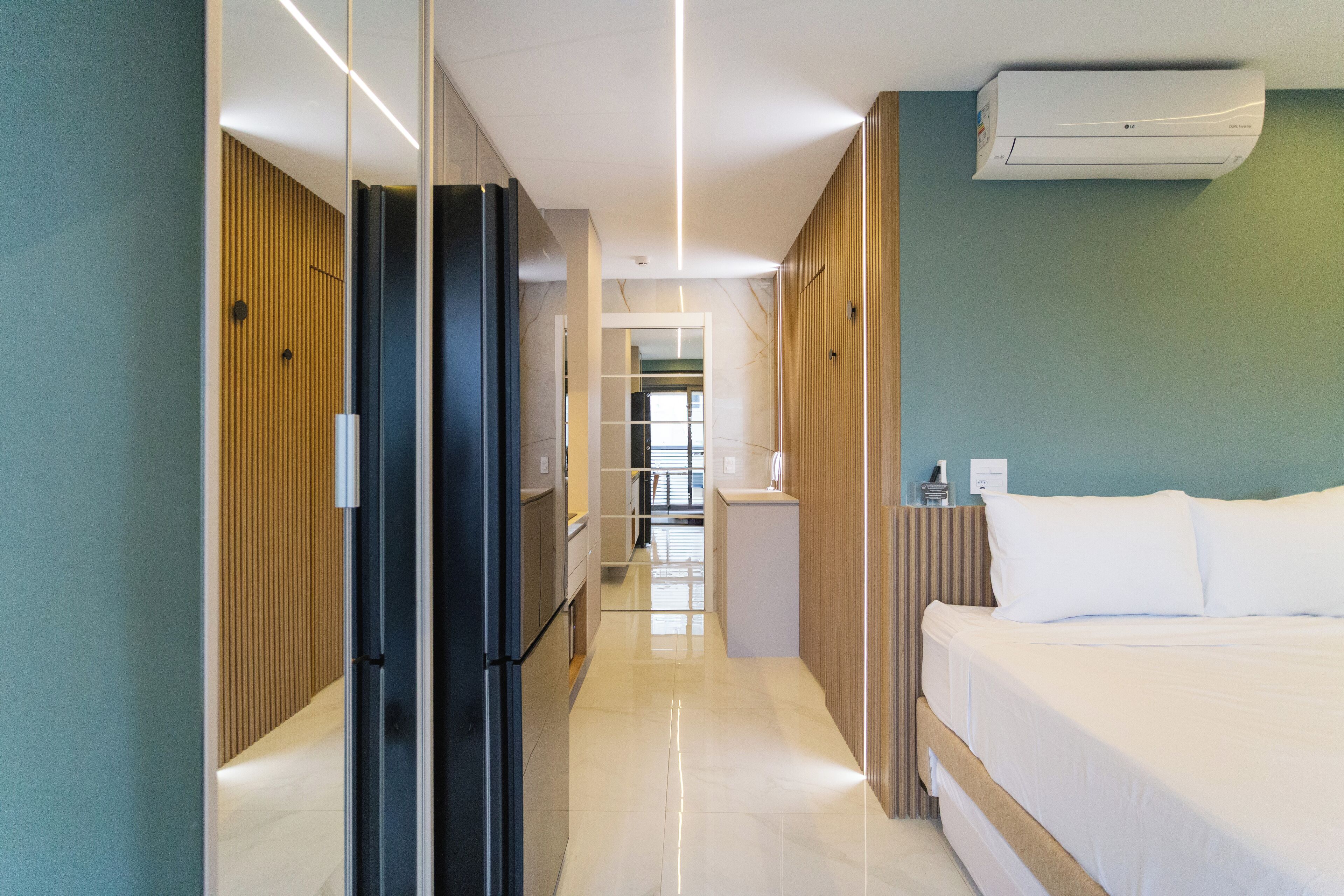 Ett modernt hotellrum med en säng, en garderob, en spegel och ett badrum som syns genom en öppen dörr.