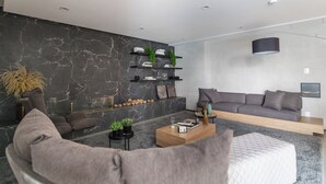 A modern living room with a dark marble wall, a grey sofa, a wooden coffee table, and a grey armchair. - Haus Mitre Alto Butantã (Sao Paulo)