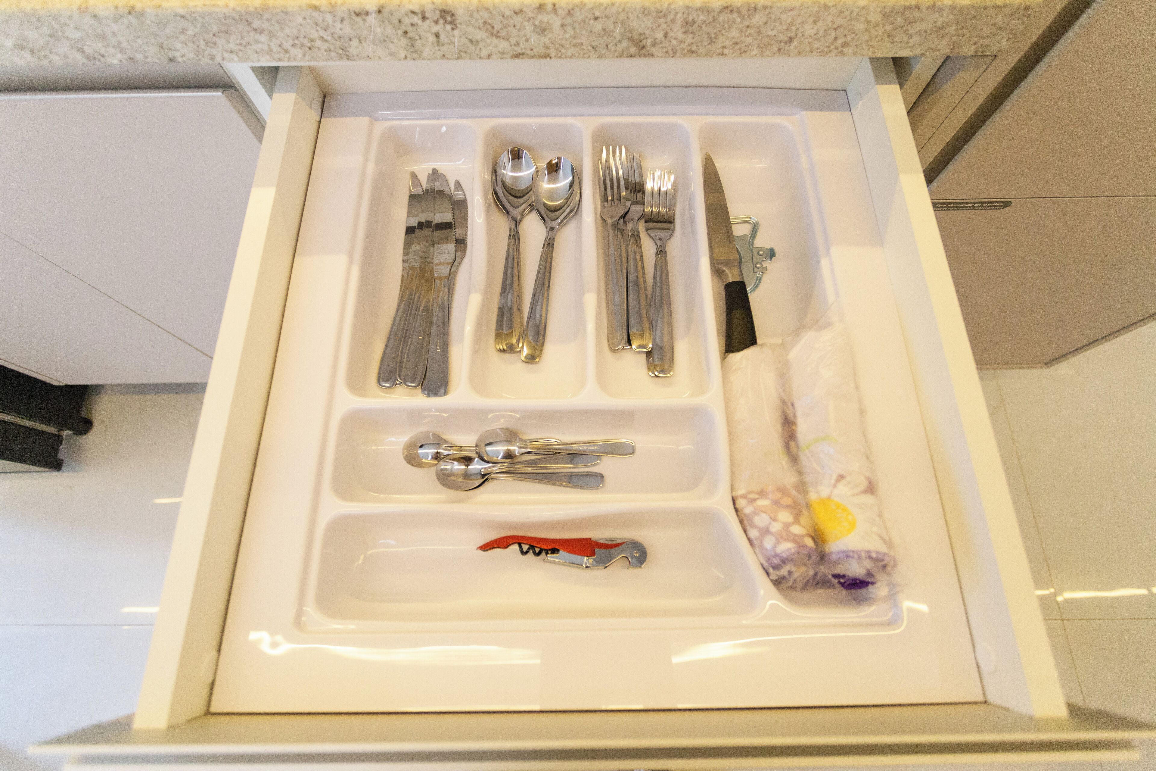 Un cajón con cubiertos ordenados, incluyendo tenedores, cucharas y un cuchillo.