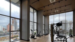 A spacious gym with large windows offering city views, various exercise equipment, and a modern interior design. - Haus Mitre Alto Butantã (Sao Paulo)