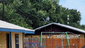 A backyard with a barbecue grill, a play structure, and a fenced area. - John Wayne Suite (Buchanan Dam)
