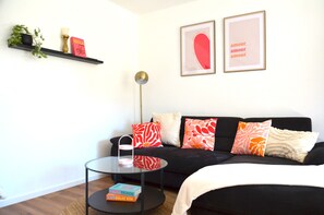 Una sala moderna con un sofá negro, una mesa de centro de vidrio y una estantería.