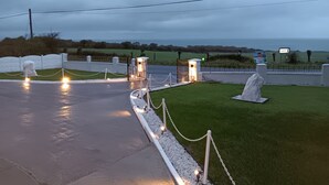 Un lieu de commémoration comprenant un chemin pavé, des statues blanches et une pelouse.