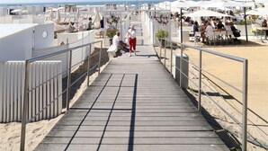 Un paseo marítimo que lleva a una terraza con mesas al aire libre y sombrillas.