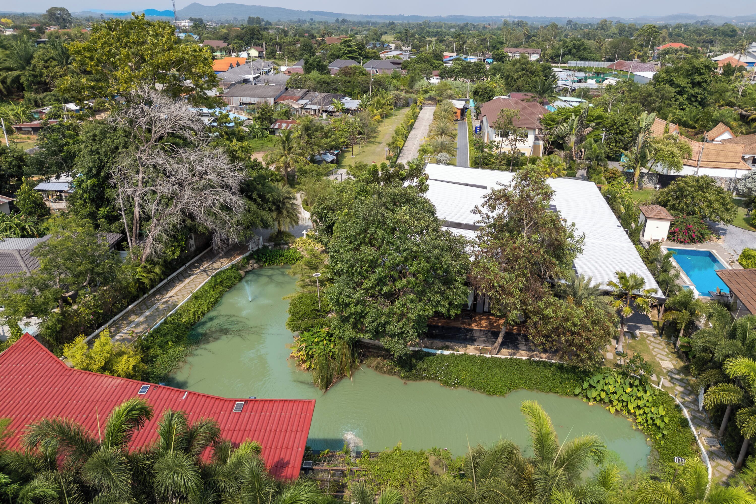 An aerial view of a residential area with houses, a river, and a swimming pool.