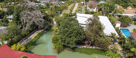 An aerial view of a residential area with houses, a river, and a swimming pool.