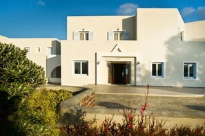 A modern building with a central entrance, multiple windows, and a paved courtyard. - De Sol Hotel & Spa (Santorini)
