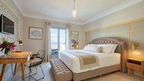 Une chambre à coucher comprenant un lit, une table de chevet, un banc, un bureau, une chaise et une vue sur l’extérieur.