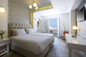 A bedroom with a large bed, a desk, and a chair. There is a balcony with a view.