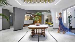 Un hall d’entrée moderne avec une table centrale, un comptoir d’accueil et une grande plante.