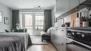A modern kitchen with grey cabinets, a built-in oven, and a window with curtains. - Modern Studios by Karolinska Institutet (Stockholm)