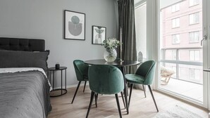 A modern bedroom with a bed, a dining table with chairs, and a large window with curtains. - Modern Studios by Karolinska Institutet (Stockholm)