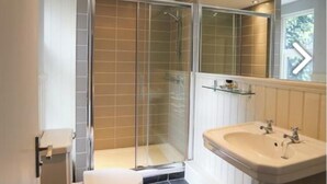 A modern bathroom with a toilet, sink, and glass-enclosed shower. - Crown and Sceptre (London)