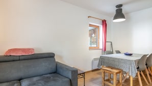 A compact living space with a grey sofa, a small wooden table, and a dining area with chairs. - Apartment in Saint-sorlin Near Ski Slopes (Saint-Sorlin-d'Arves)