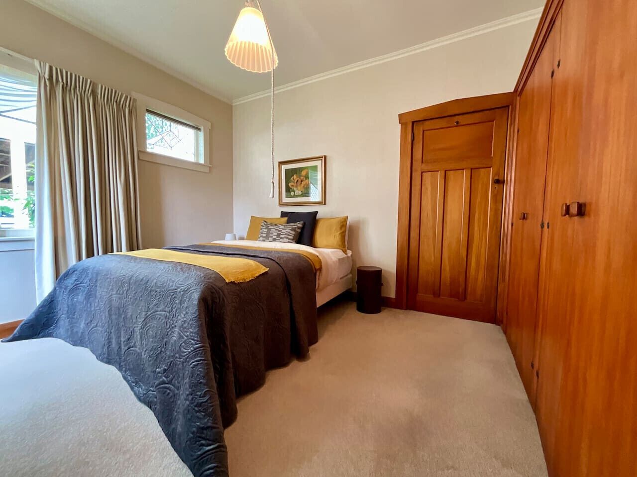 Un dormitorio con dos camas, un armario de madera, una ventana con cortinas y una lámpara colgante.
