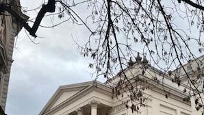 A classical building with columns and a statue in front.
