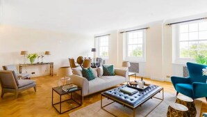 A spacious living room with a sofa, armchairs, a coffee table, and a blue armchair.