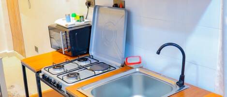 A compact kitchenette with a gas stove, sink, and wooden countertops.