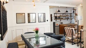 A modern dining area with a glass table, cushioned chairs, and a vase of flowers. - Sandalwood Suites Nakuru (Nakuru)