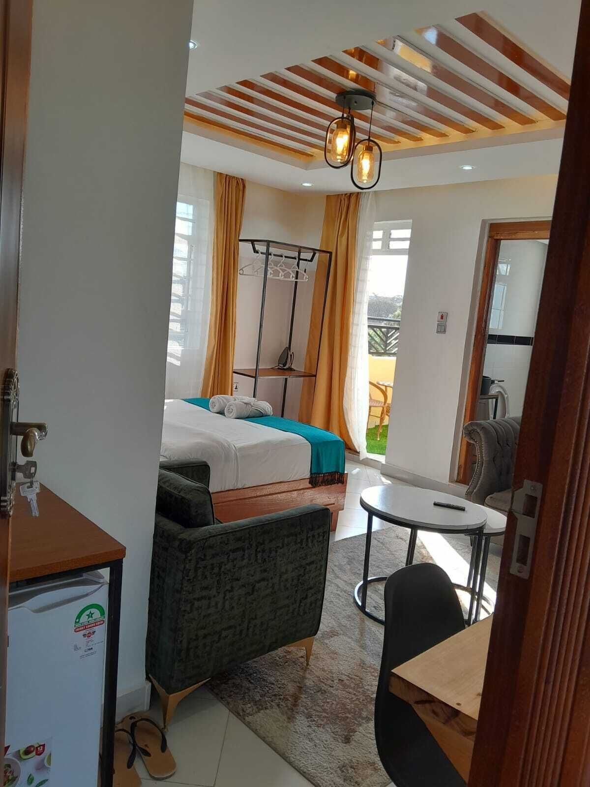 A hotel room with a bed, a desk, a chair, a small table, and a balcony with a view.