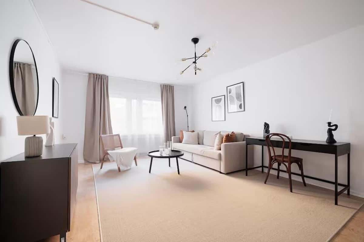A modern living room with a sofa, coffee table, and a desk with a chair.