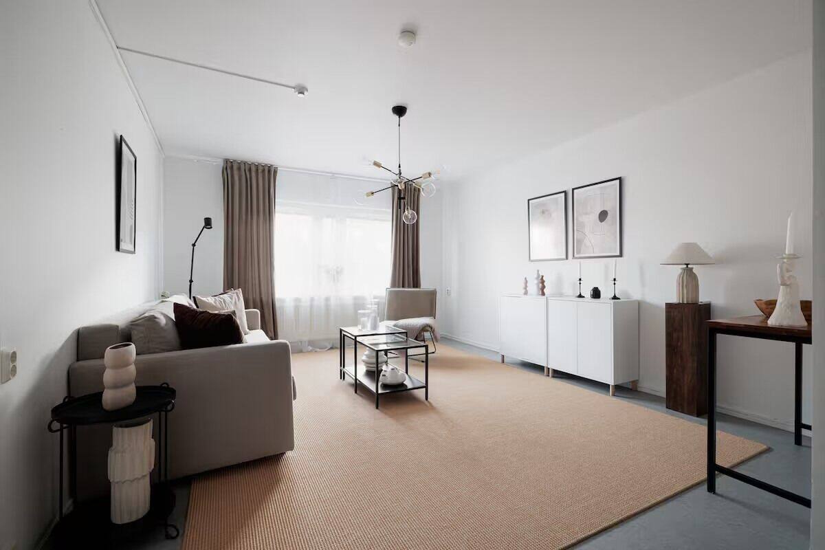 A modern living room with a sofa, coffee table, and a dining area.