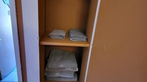 A small storage space with shelves holding folded towels.