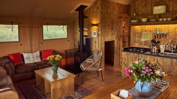 Een knusse woonkamer met een bank, een bijzettafeltje en een open haard.