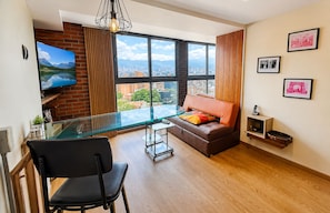 Una sala de estar moderna con una mesa de comedor de vidrio, un sofá de cuero y vistas a la ciudad a través de amplias ventanas.