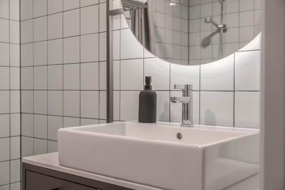 A bathroom with a white sink, a mirror, and a shower.
