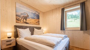 A bedroom with a bed, nightstand, and a painting of a mountain scene. - Apartment in Oberwolz Near Ski Slope (Oberwölz)